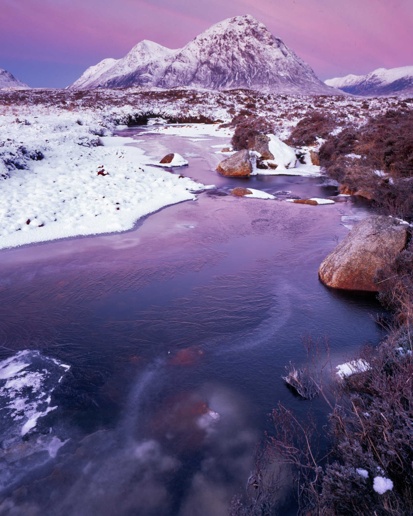 Buachaille Etive Mòr under snow at dawn, a pink sky over the frozen river on Rannoch Moor