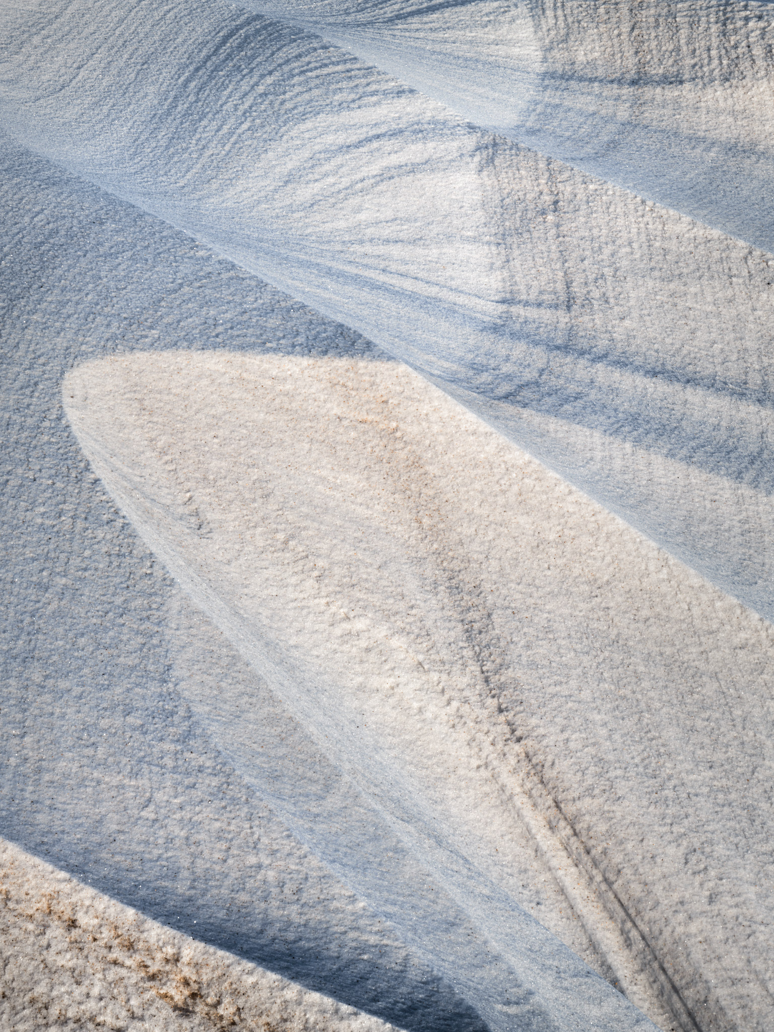 Wind-carved sastrugi ridges flowing in diagonal blades across the Icelandic snow