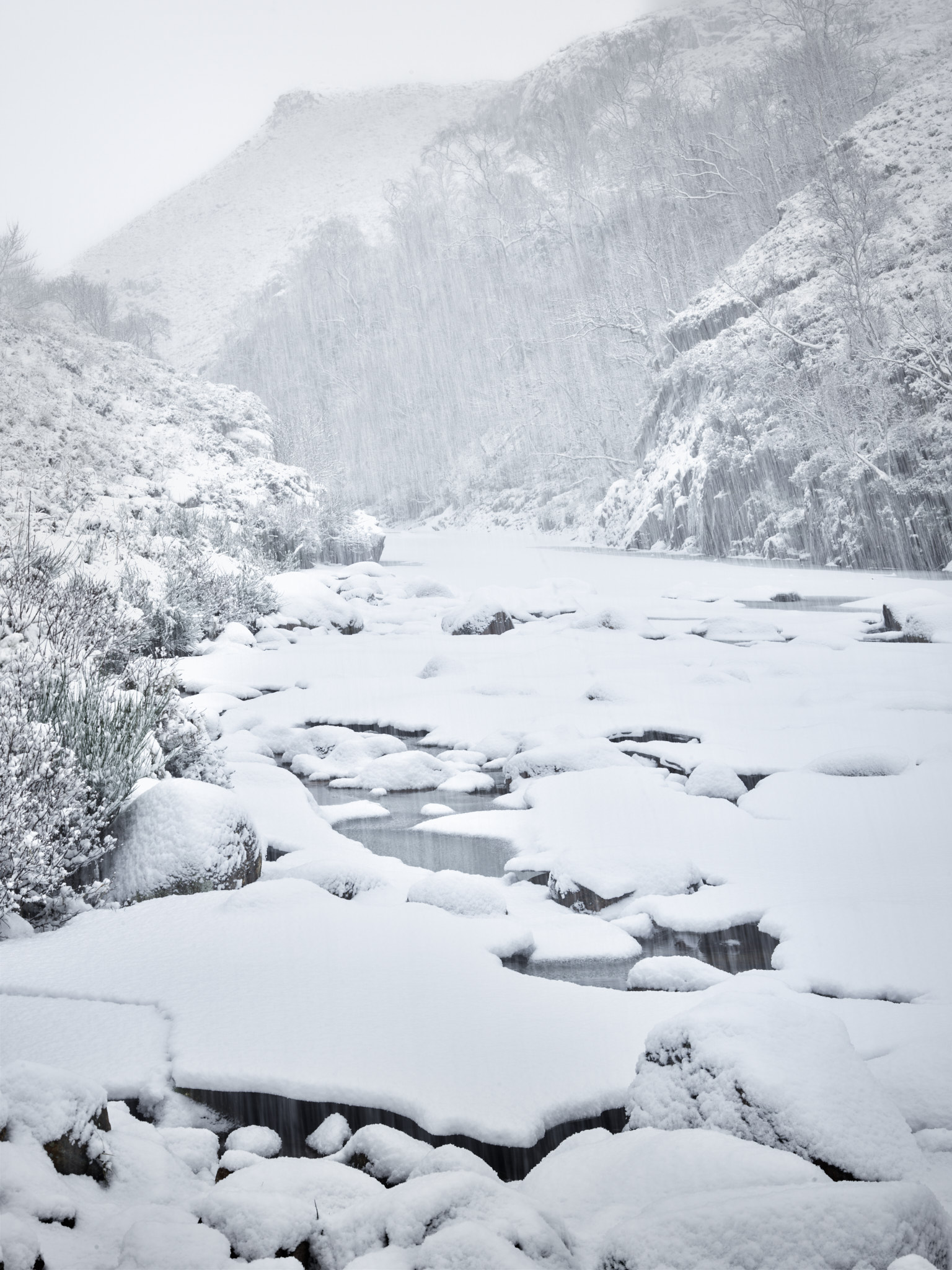 Heavy snow falling on the frozen, ice-blocked River Etive